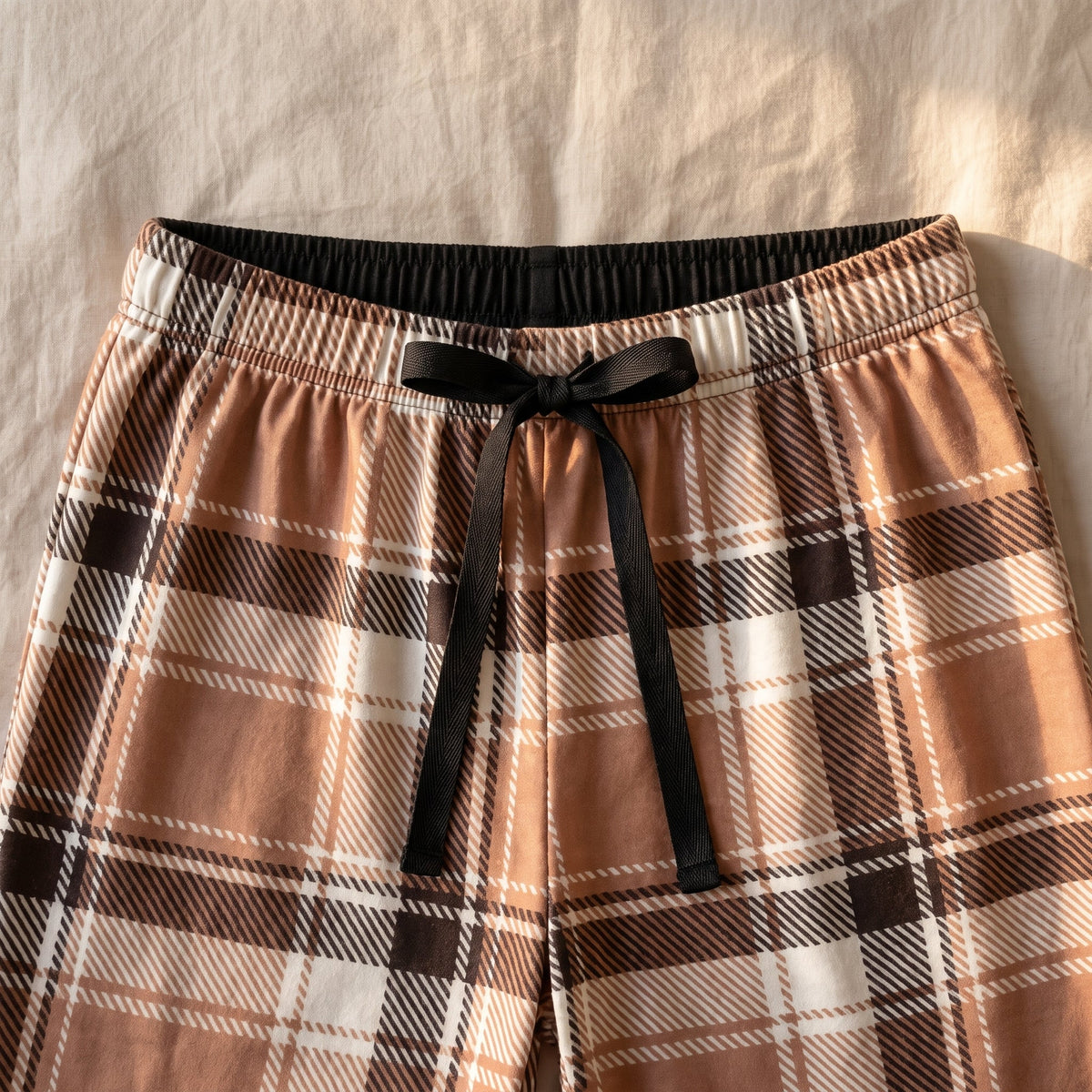Gros plan de la taille elastiquee et du cordon plat noue du pantalon de pyjama a carreaux