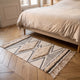 Le petit format 60 x 90 cm du tapis ethnique posé au pied d'un lit, ses deux losanges tuftés côte à côte