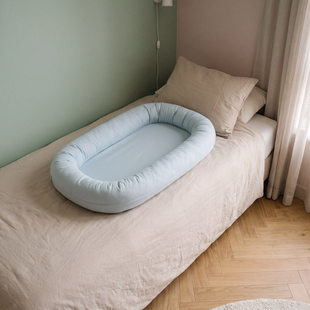 Couffin bébé en coton posé sur le lit, coloris bleu gris