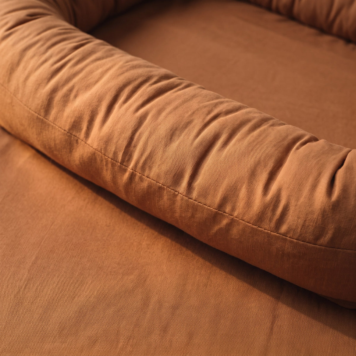 Le bourrelet matelassé et le couchage du couffin bébé en coton caramel, de tout près