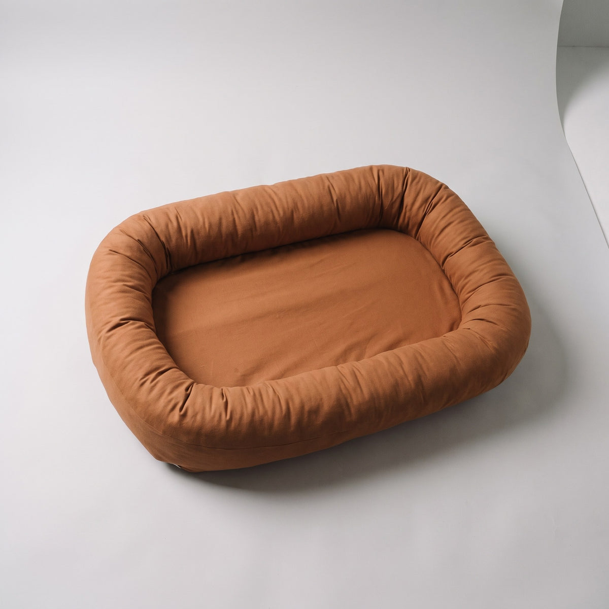 Couffin bébé en coton caramel seul sur fond clair, le bourrelet fait le tour du couchage