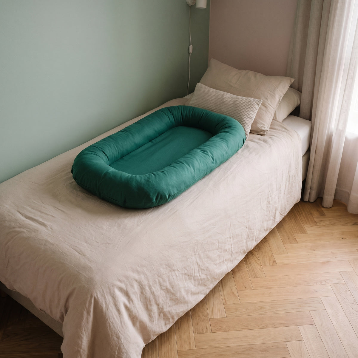 Couffin bébé en coton posé sur le lit, coloris vert sapin