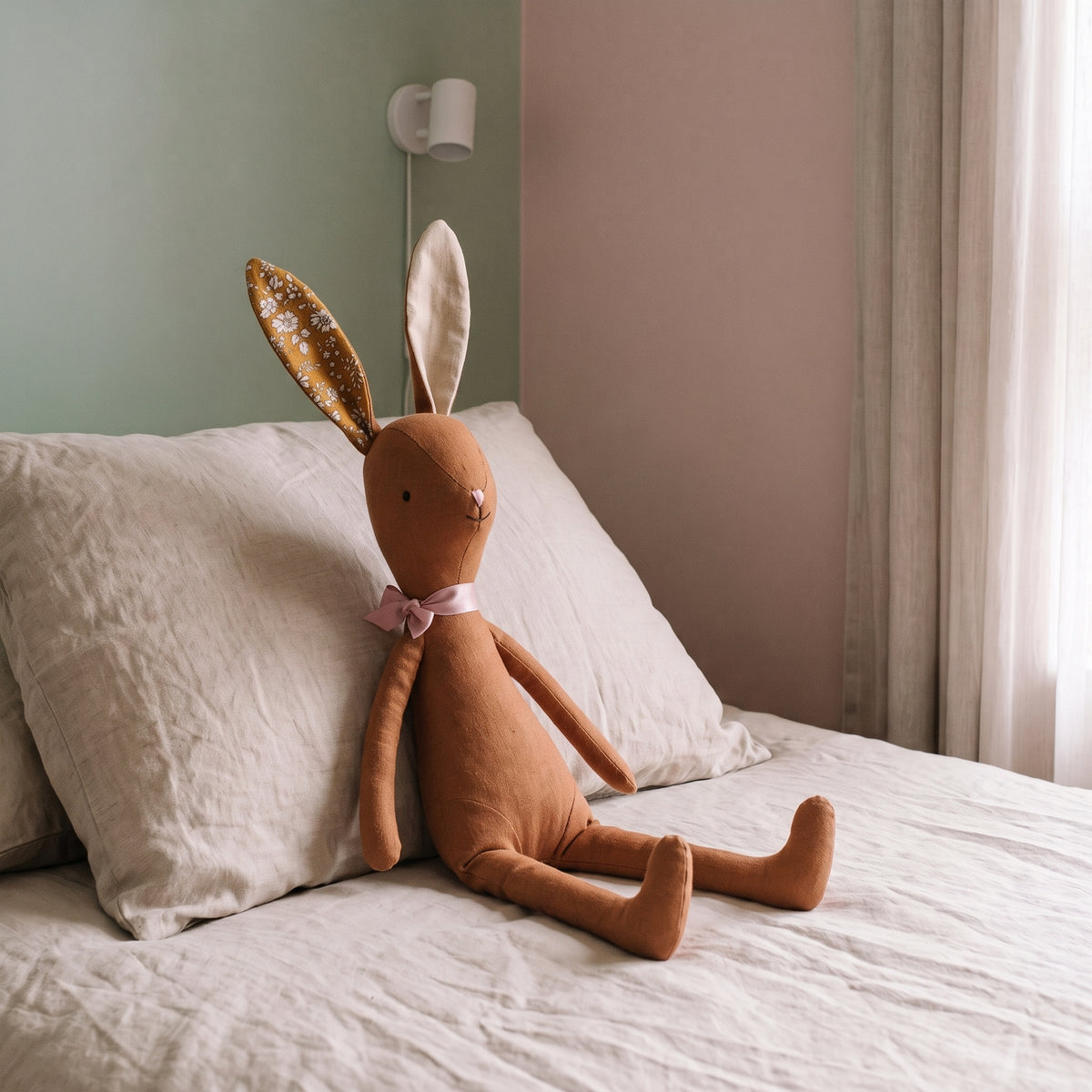 Doudou lapin marron assis sur le lit, échelle réelle