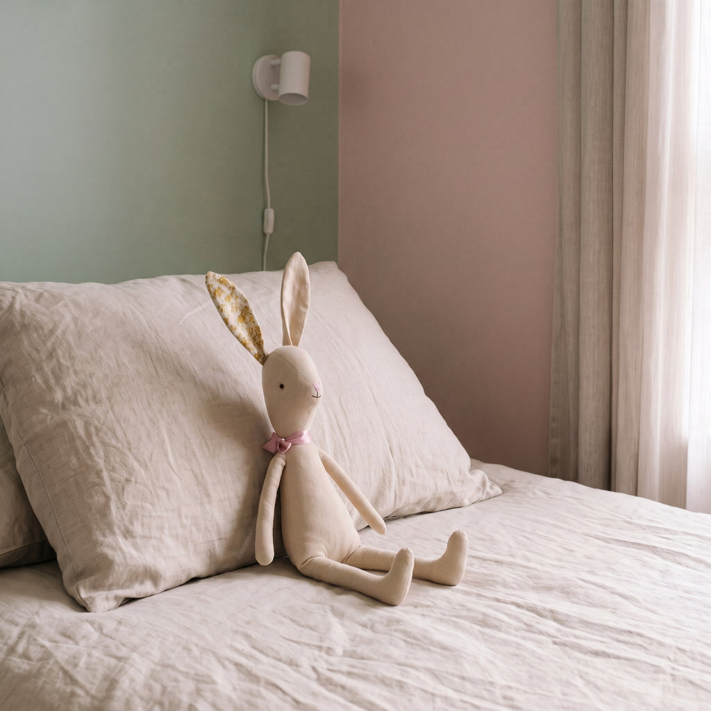 Doudou lapin beige adossé à l oreiller, échelle réelle