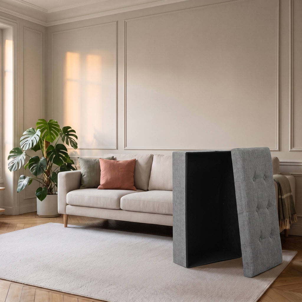 Tabouret coffre replié à plat, ses panneaux minces debout contre le canapé