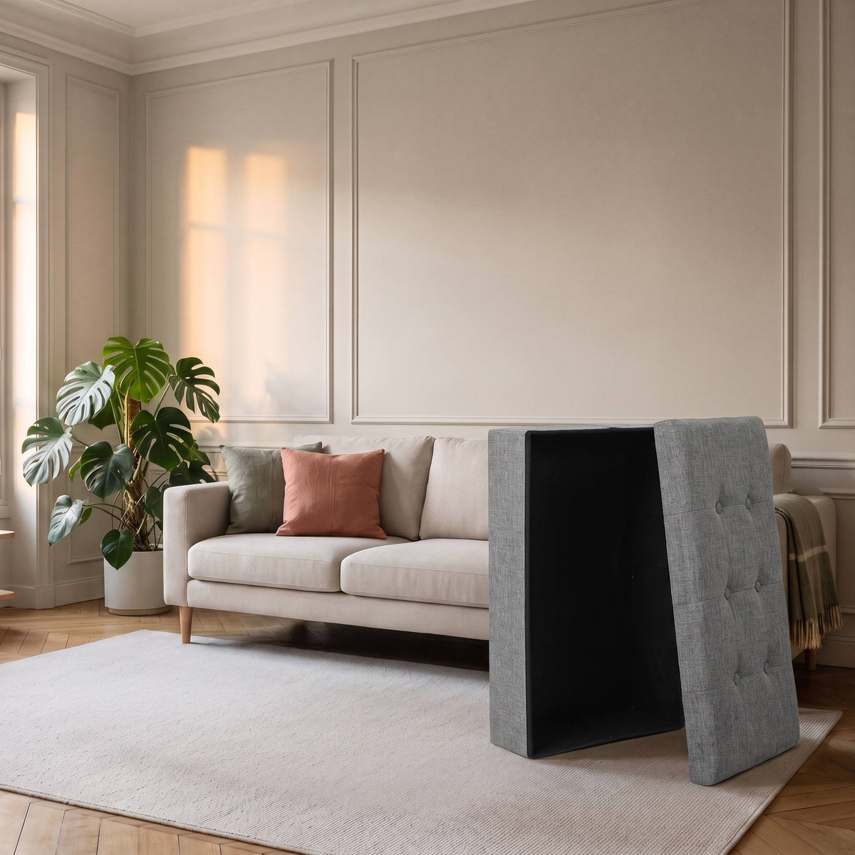 Tabouret coffre replié à plat, ses panneaux minces debout contre le canapé
