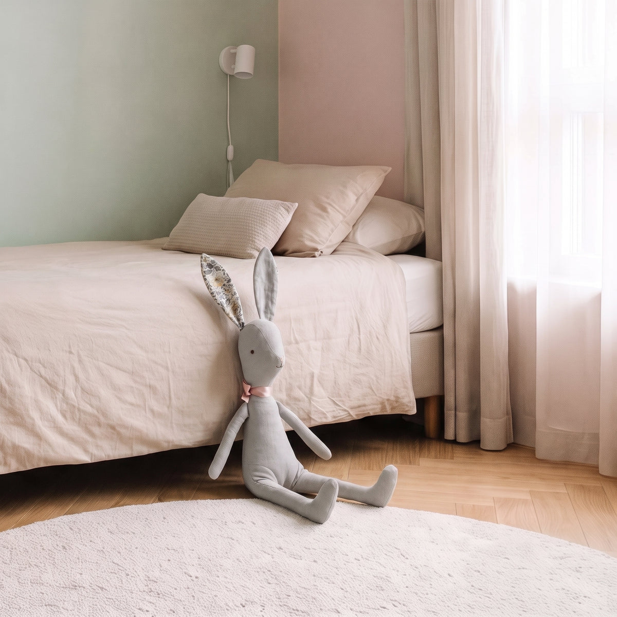 Doudou lapin gris assis au pied du lit, échelle réelle