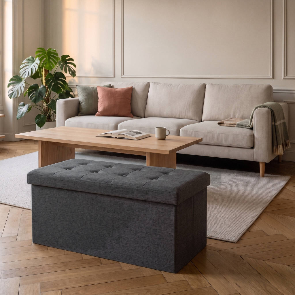 Tabouret coffre de rangement pliable gris lin sur un parquet en point de Hongrie