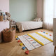 Petit tapis coloré posé au pied d'un lit dans une chambre d'enfant
