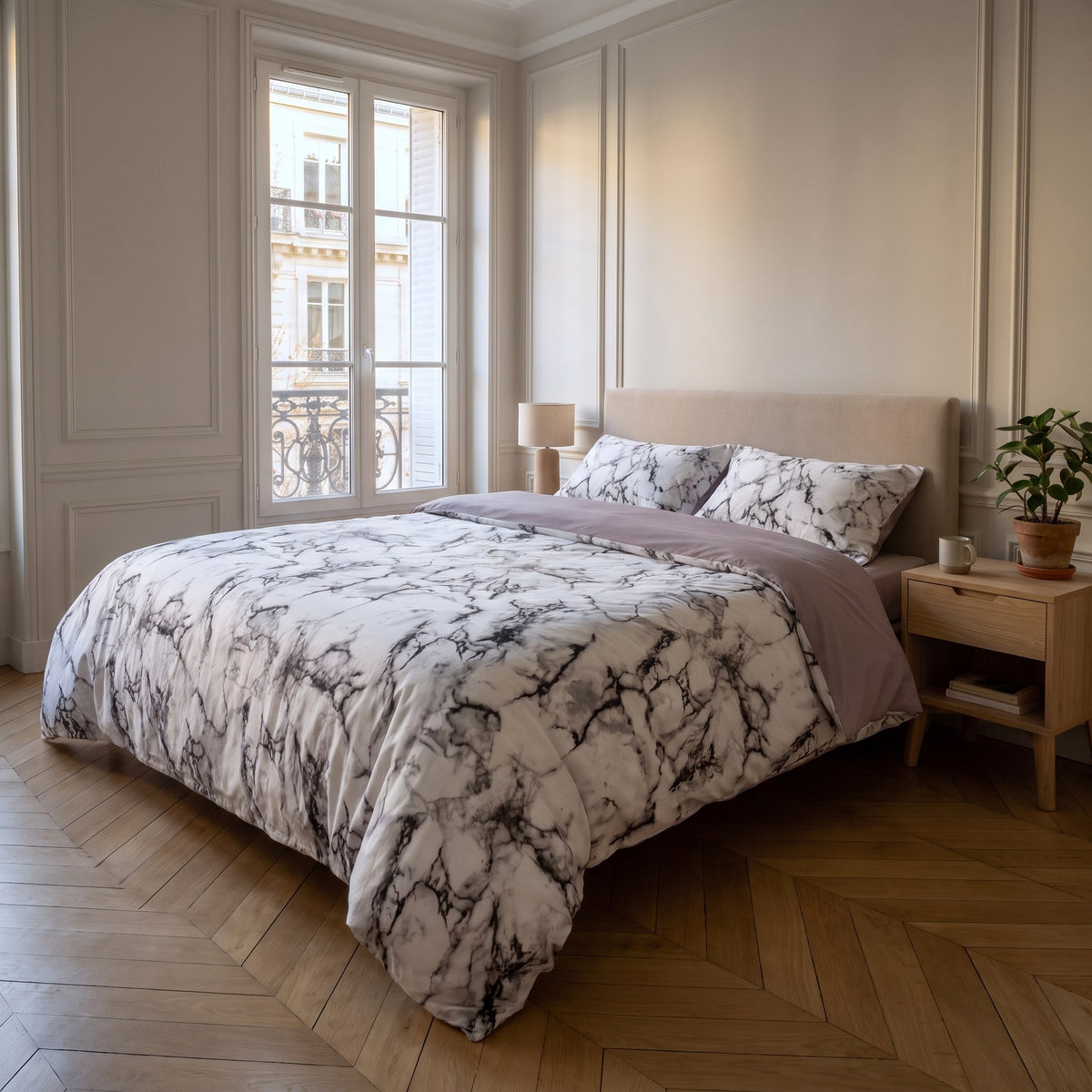 Housse de couette marbrée blanche sur un lit deux places, le rabat découvre l'envers uni mauve