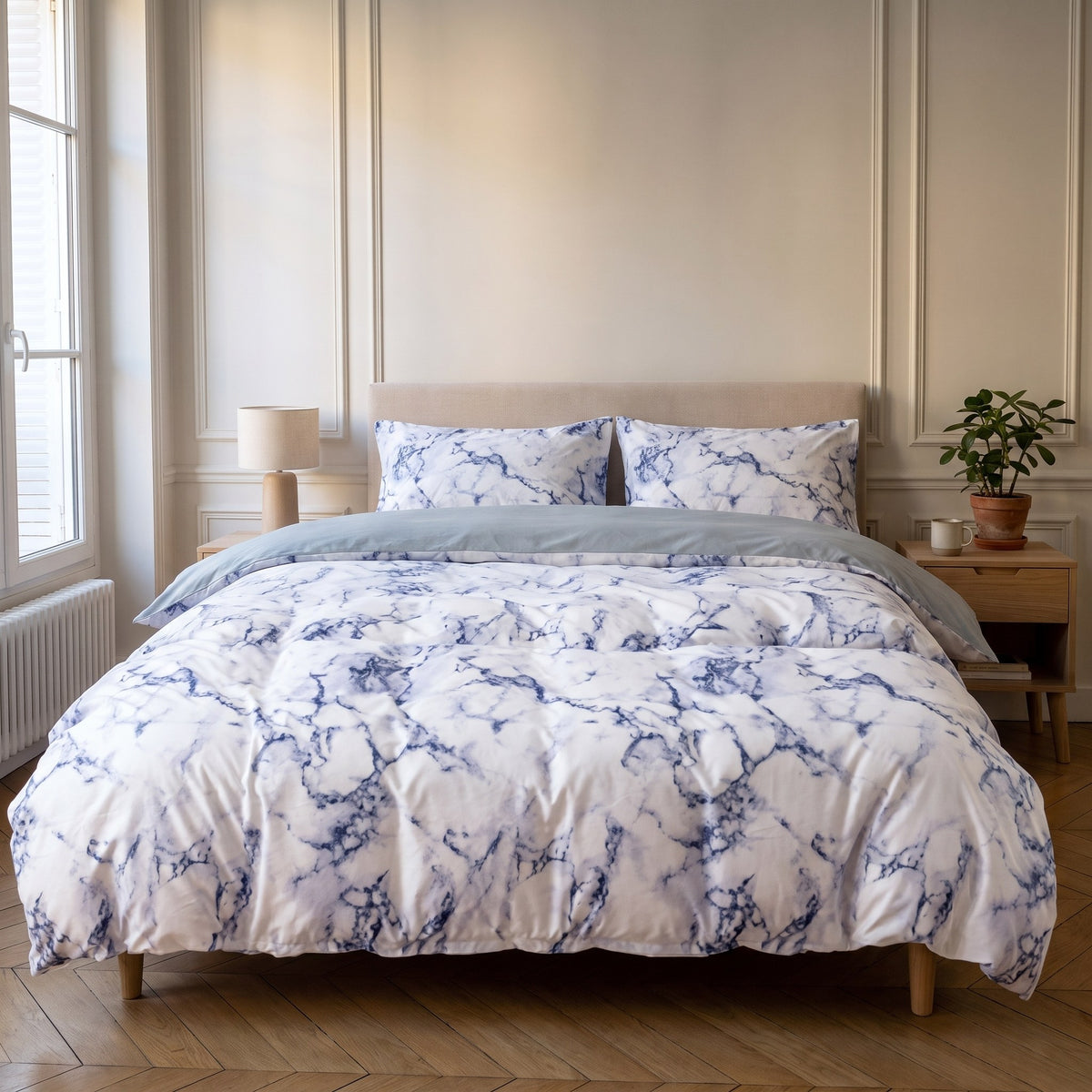 Housse de couette marbrée bleue sur un lit deux places, rabat sur l'envers uni bleu clair