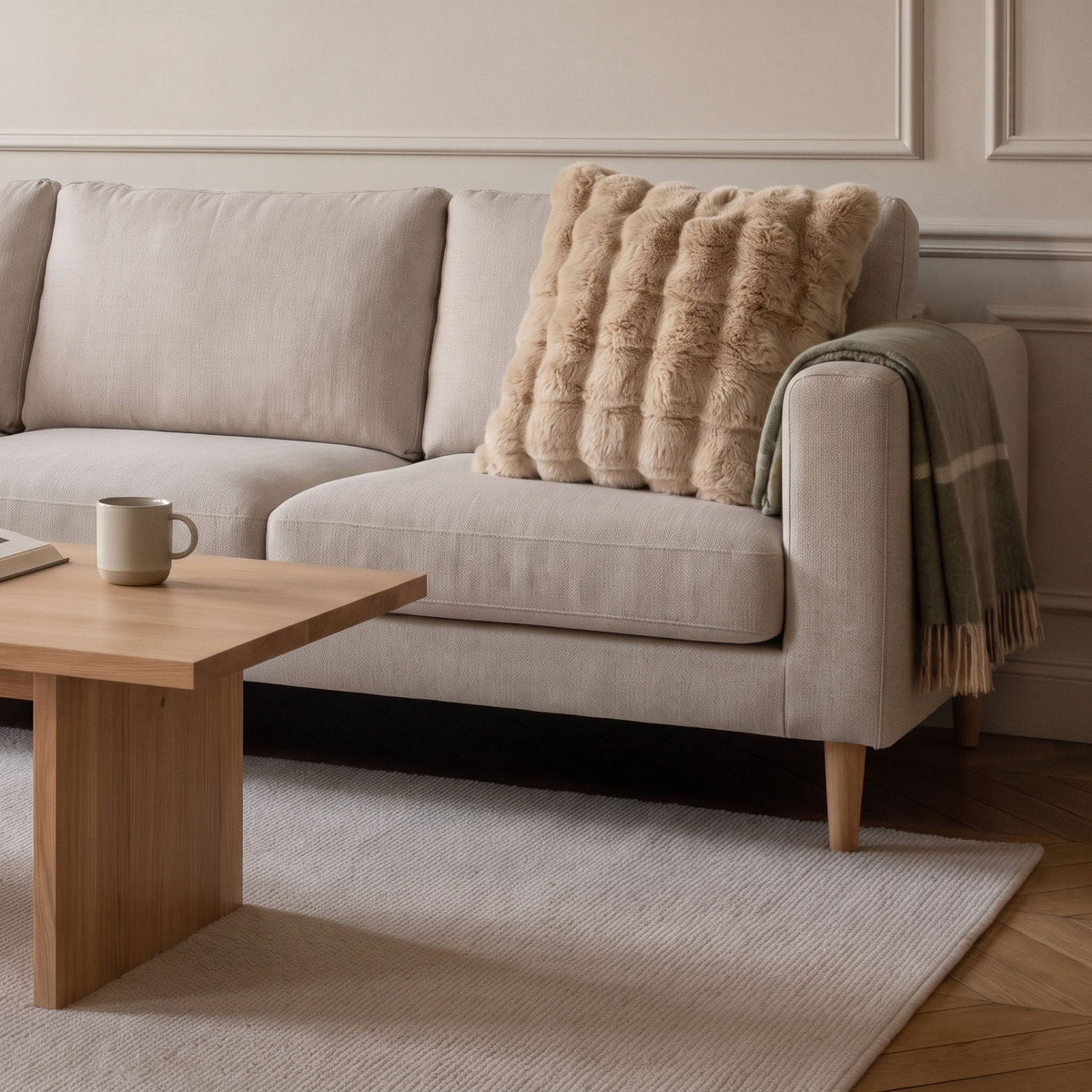 Coussin carré en fausse fourrure beige posé sur le canapé d'un salon clair