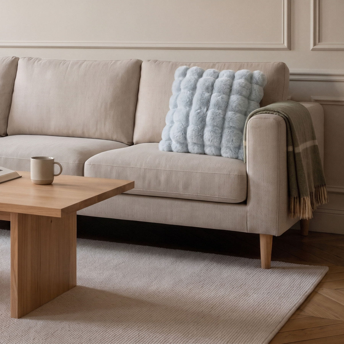 Coussin carré en fausse fourrure bleue posé sur le canapé d'un salon clair