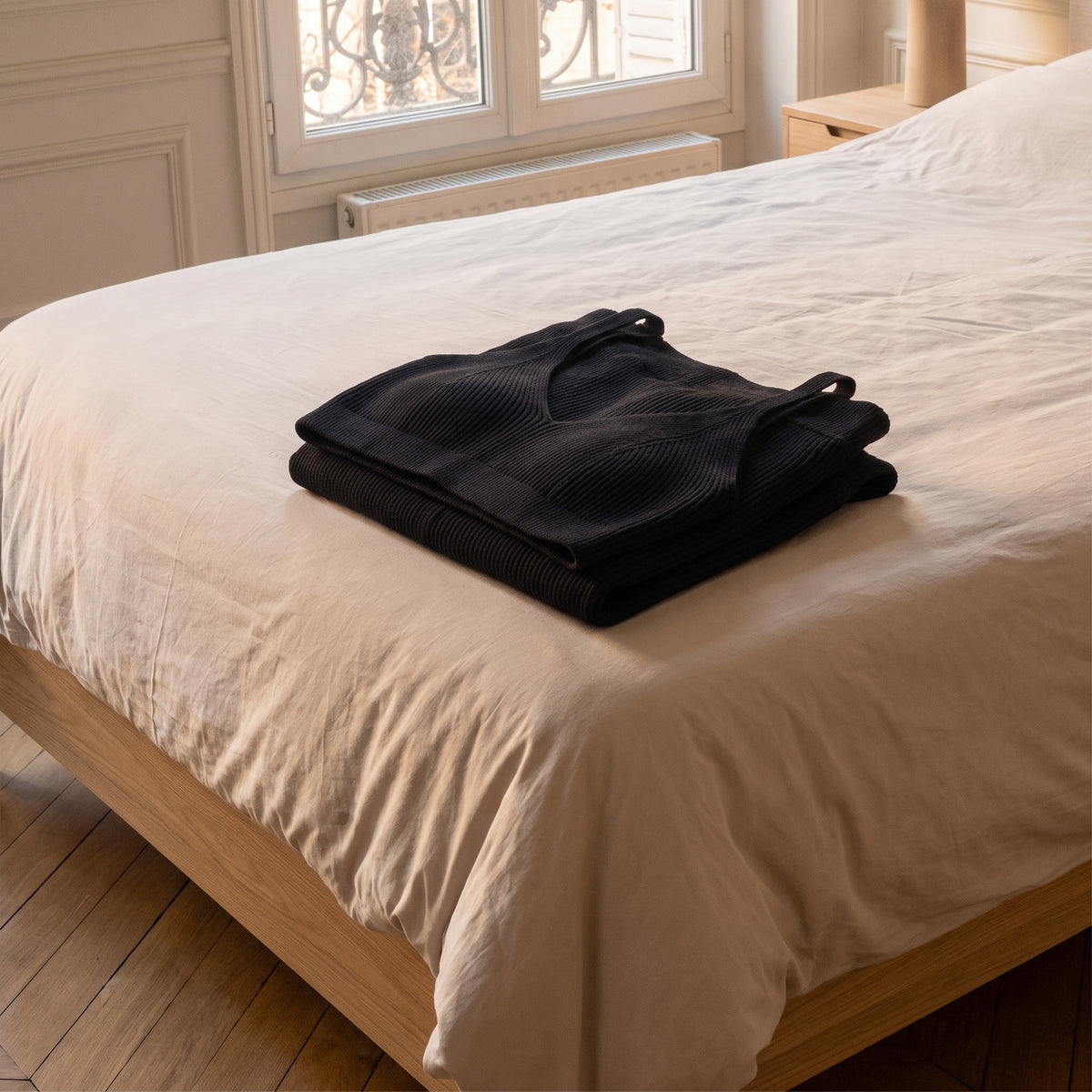 Ensemble en maille côtelée noir plié au pied du lit