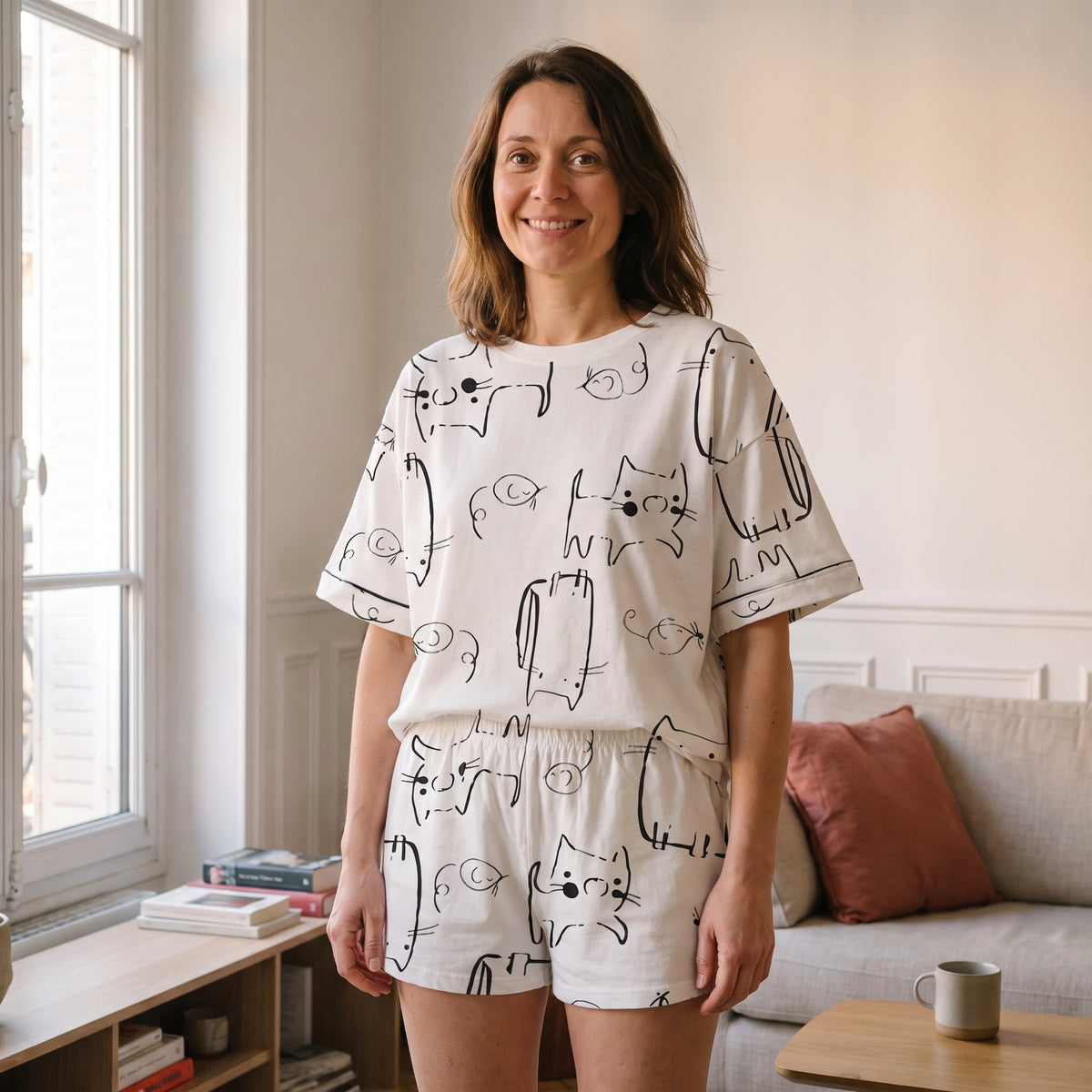 Pyjama court femme en coton imprimé chats porté debout dans un salon