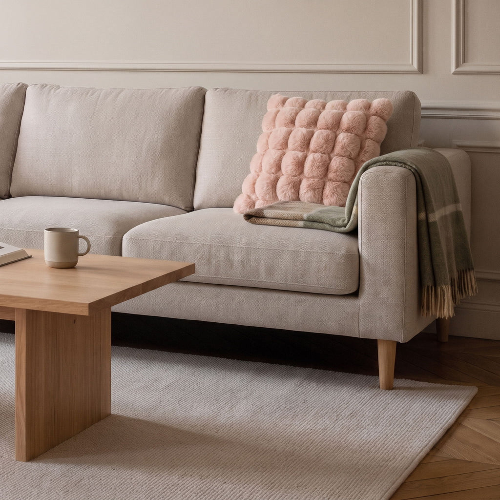 Coussin carré en fausse fourrure rose posé sur le canapé d'un salon clair