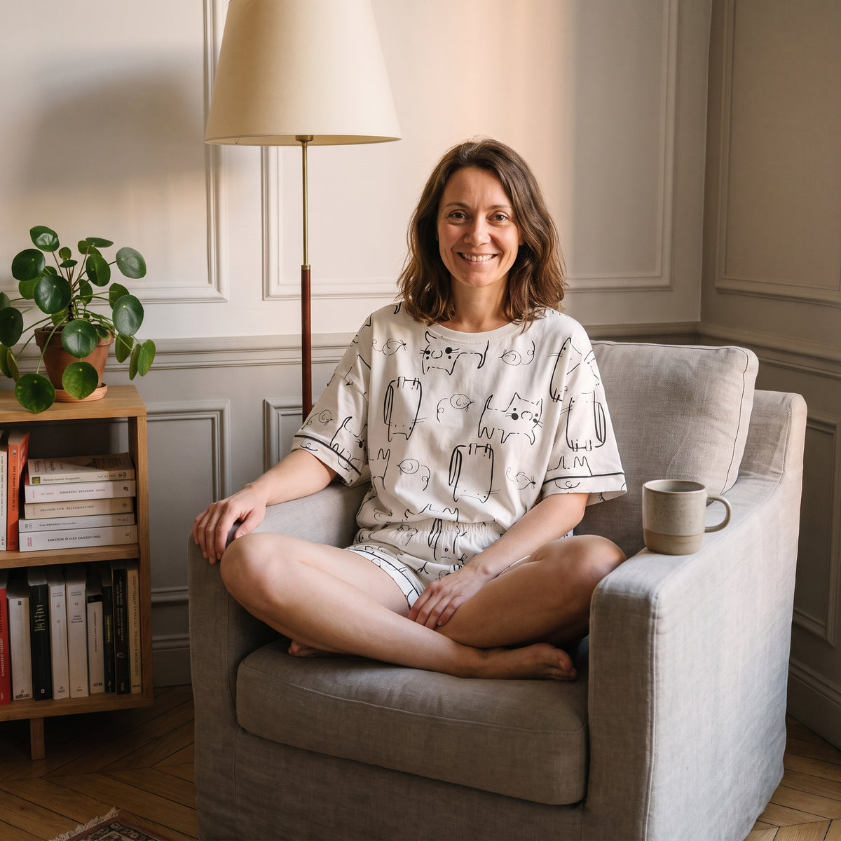 Femme installée dans un fauteuil de lecture en pyjama court imprimé chats