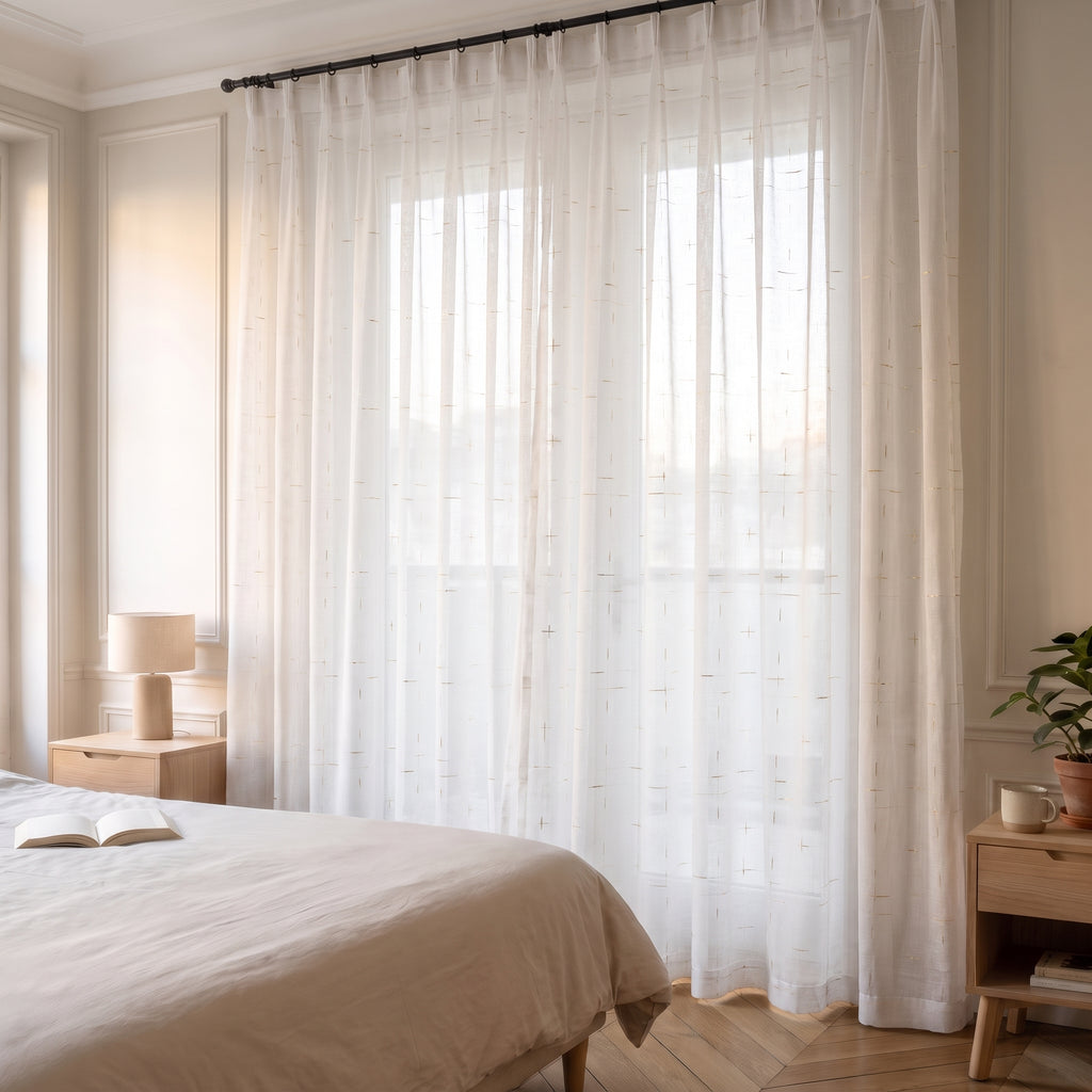 Voilage blanc à fins tirets dorés devant la fenêtre entière d’une chambre