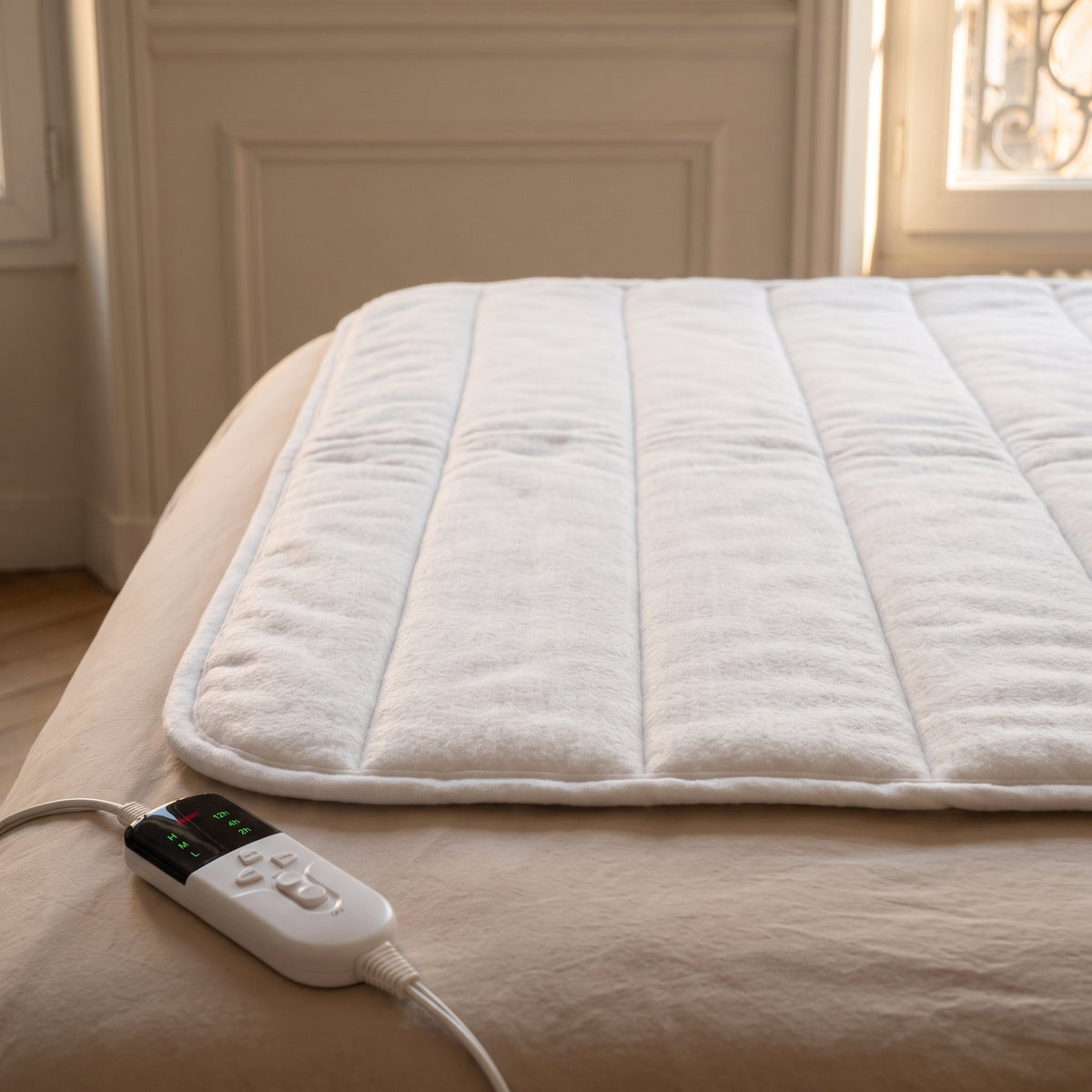 Détail du matelassage en canaux, du bord ourlé et d'un boîtier de commande de la couverture chauffante