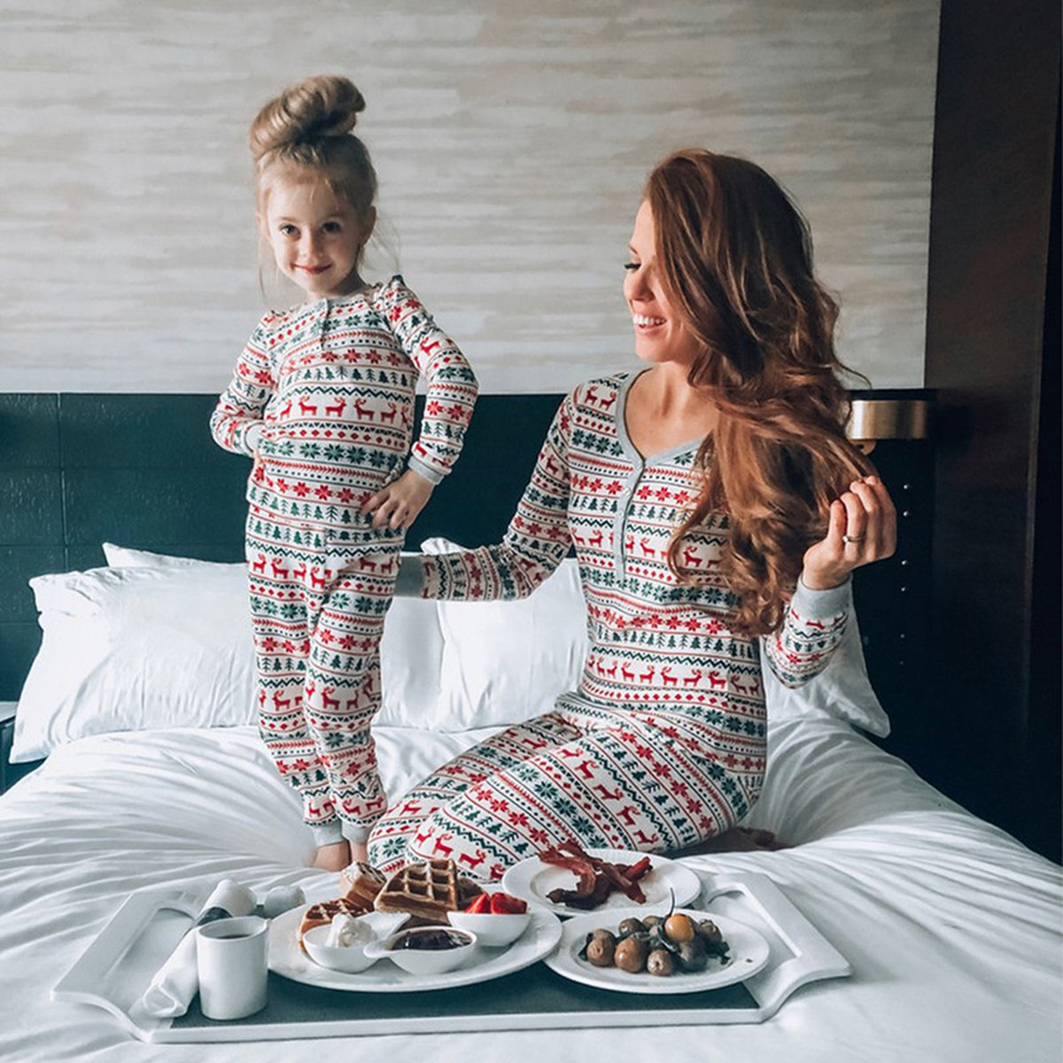 Mère et enfant en pyjamas de Noël familiaux sur un lit