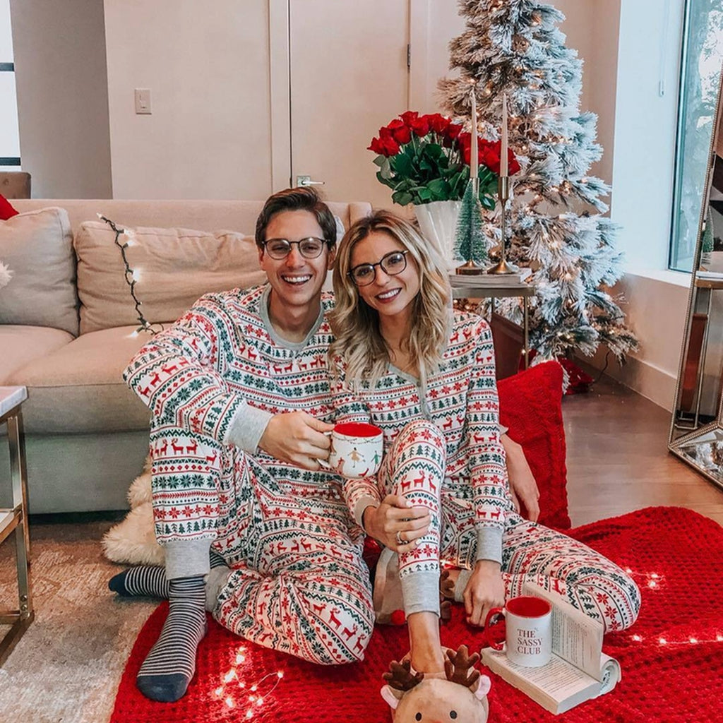 Une femme et un homme en pyjamas de Noël blancs assortis dans le salon