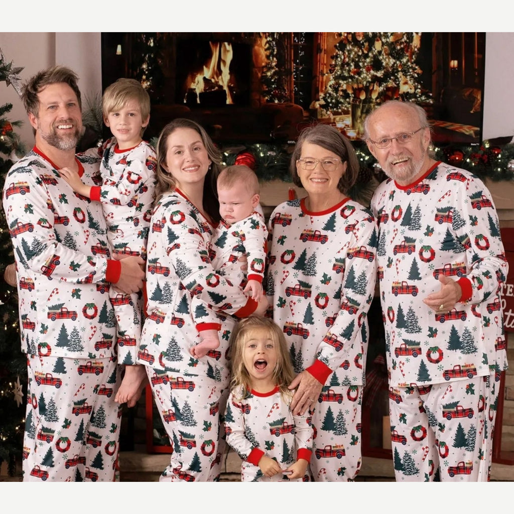 Famille en pyjamas de Noël blancs assortis à sapins et voitures, cadrage rapproché