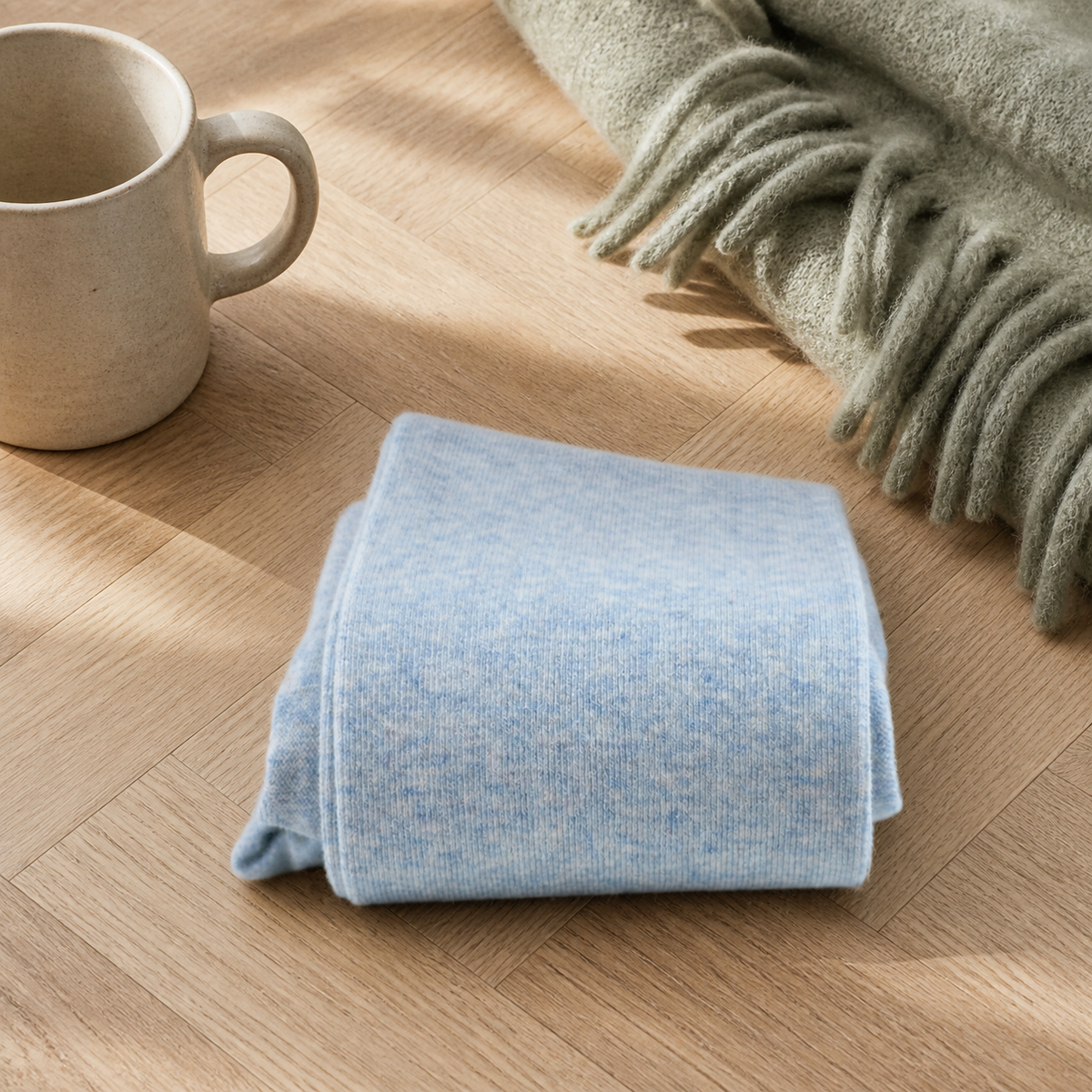 Chaussettes hautes femme coloris bleu clair pliées sur un parquet clair