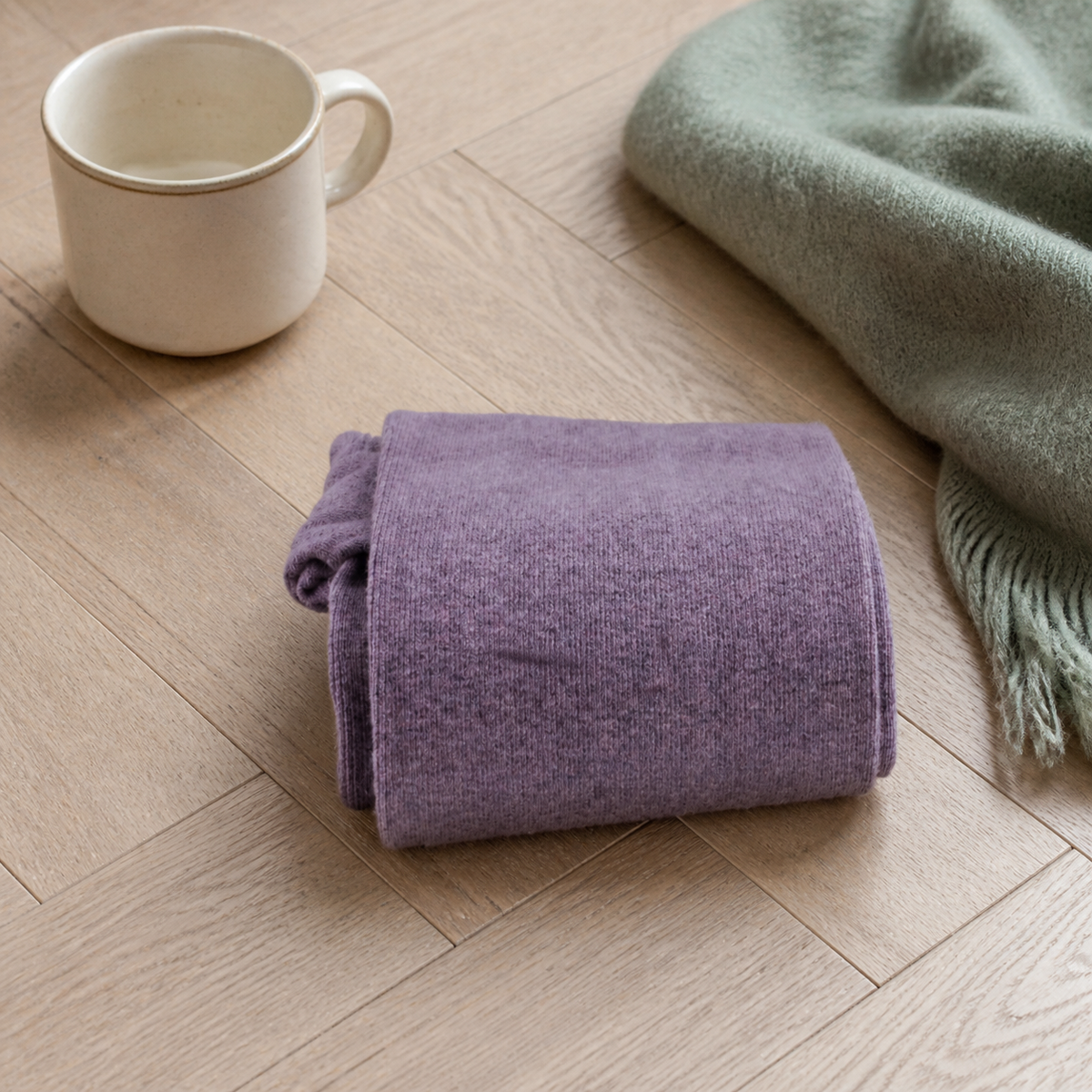 Chaussettes hautes femme coloris violet pliées sur un parquet clair