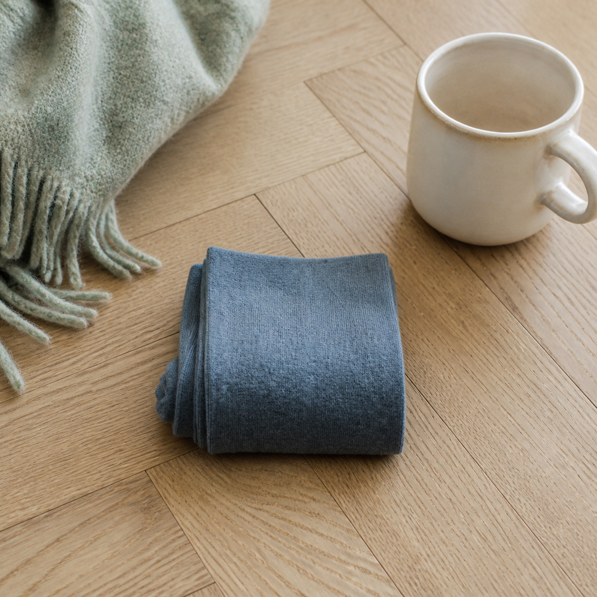 Chaussettes hautes femme coloris bleu foncé pliées sur un parquet clair