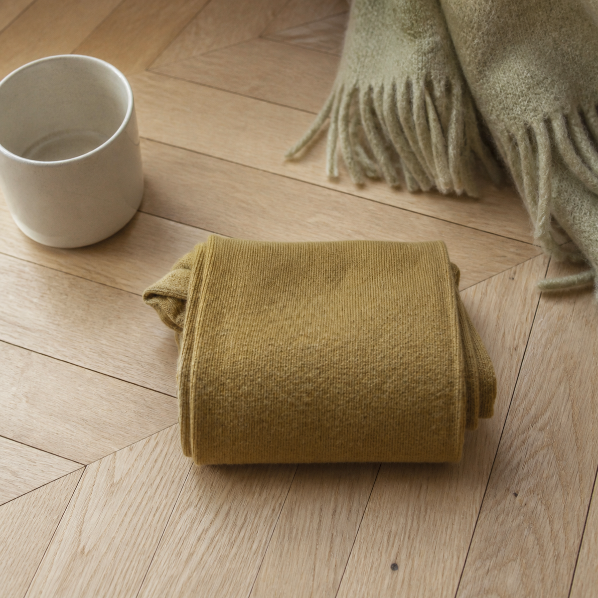 Chaussettes hautes femme coloris jaune pliées sur un parquet clair