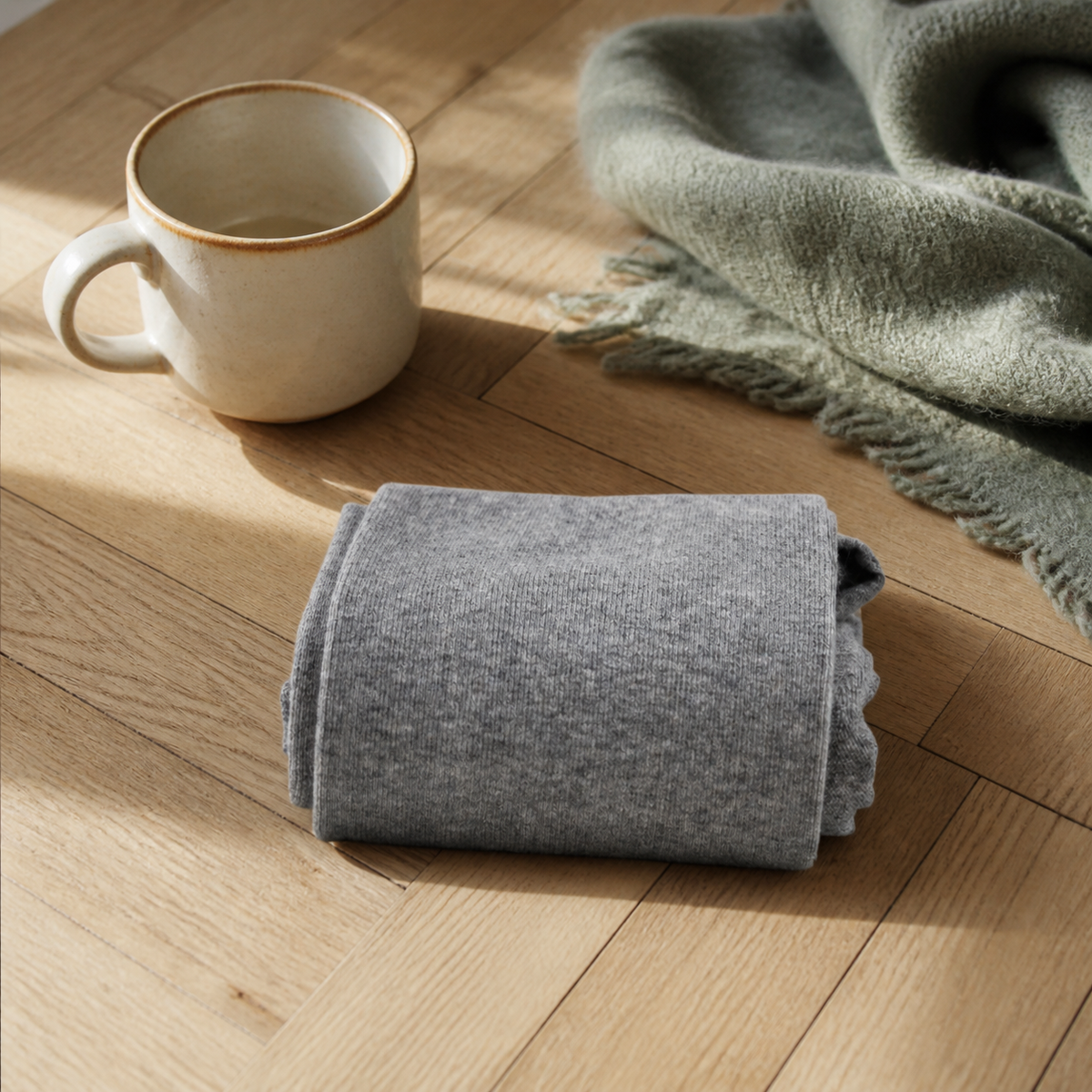 Chaussettes hautes femme coloris gris clair pliées sur un parquet clair