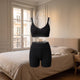 Ensemble d'intérieur femme en maille côtelée noir, débardeur et short, dans une chambre