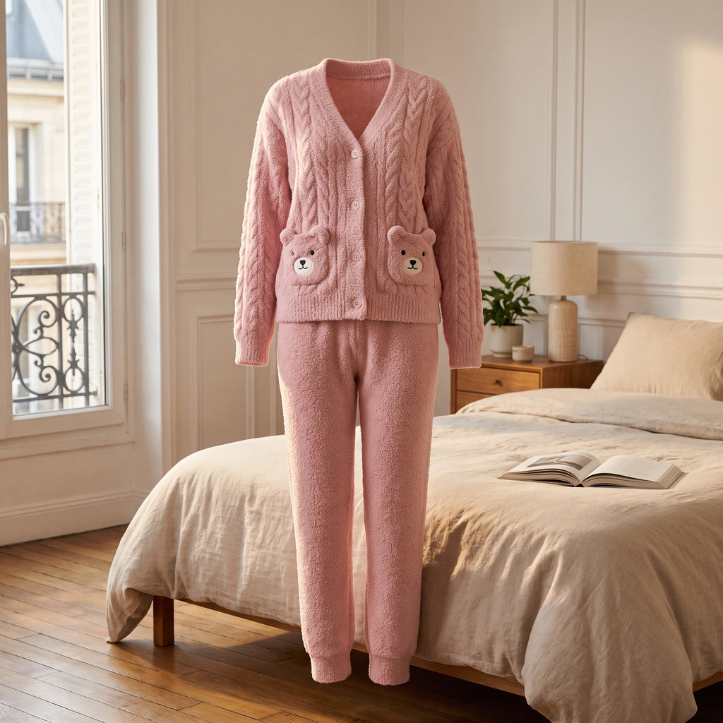 Pyjama en peluche ourson rose présenté en volume, haut boutonné et pantalon, dans une chambre