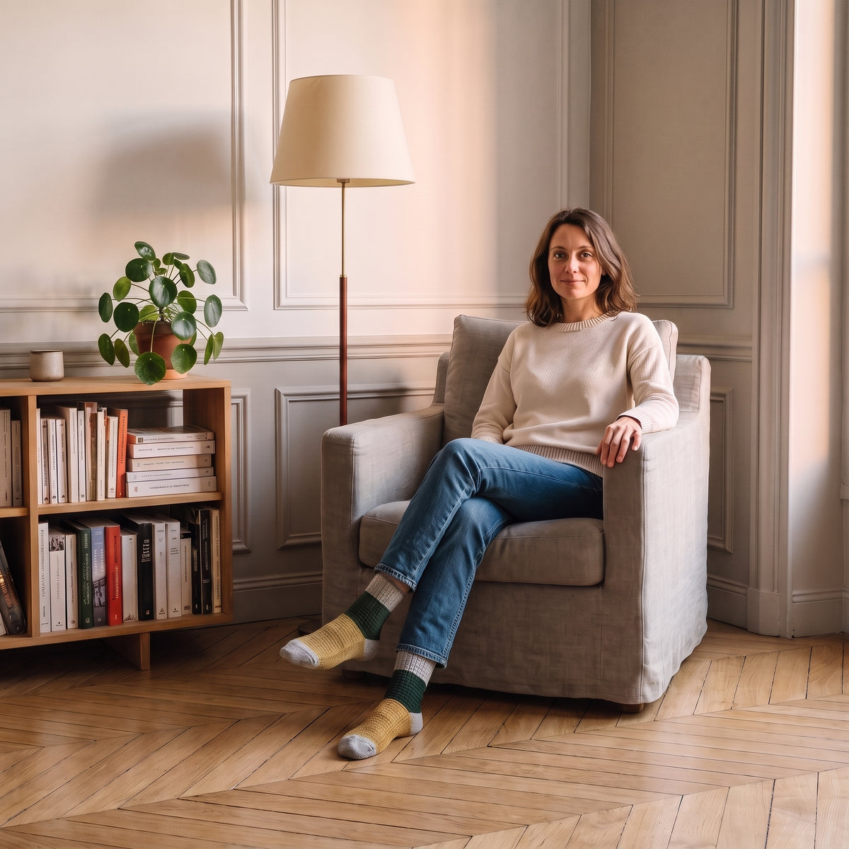 Chaussettes tricolores gris sapin et moutarde portées aux pieds dans un coin lecture