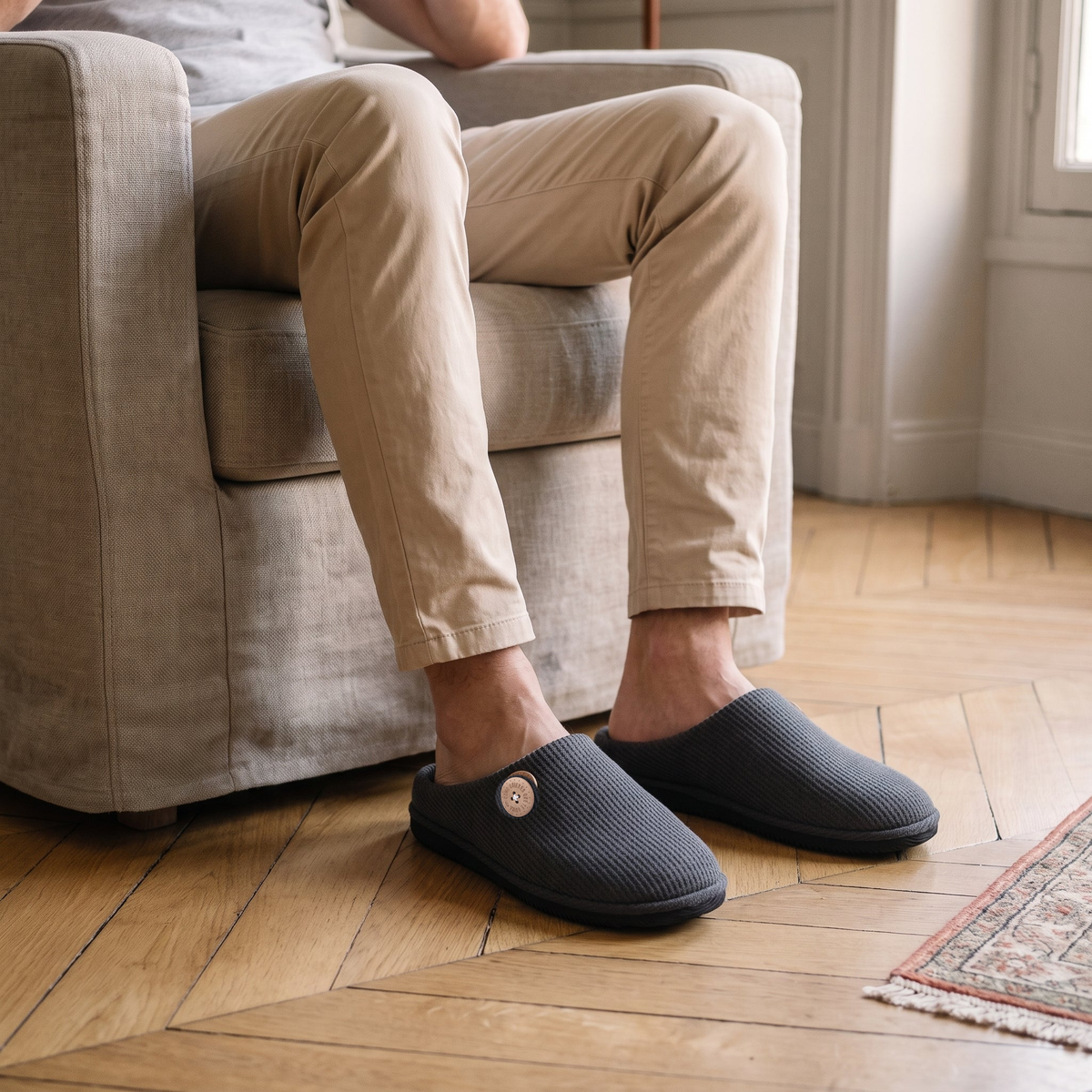 Chaussons homme gris foncé portés dans le salon