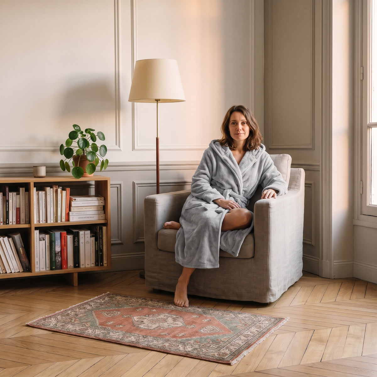 Femme du casting en robe de chambre longue Grise assise dans le coin lecture