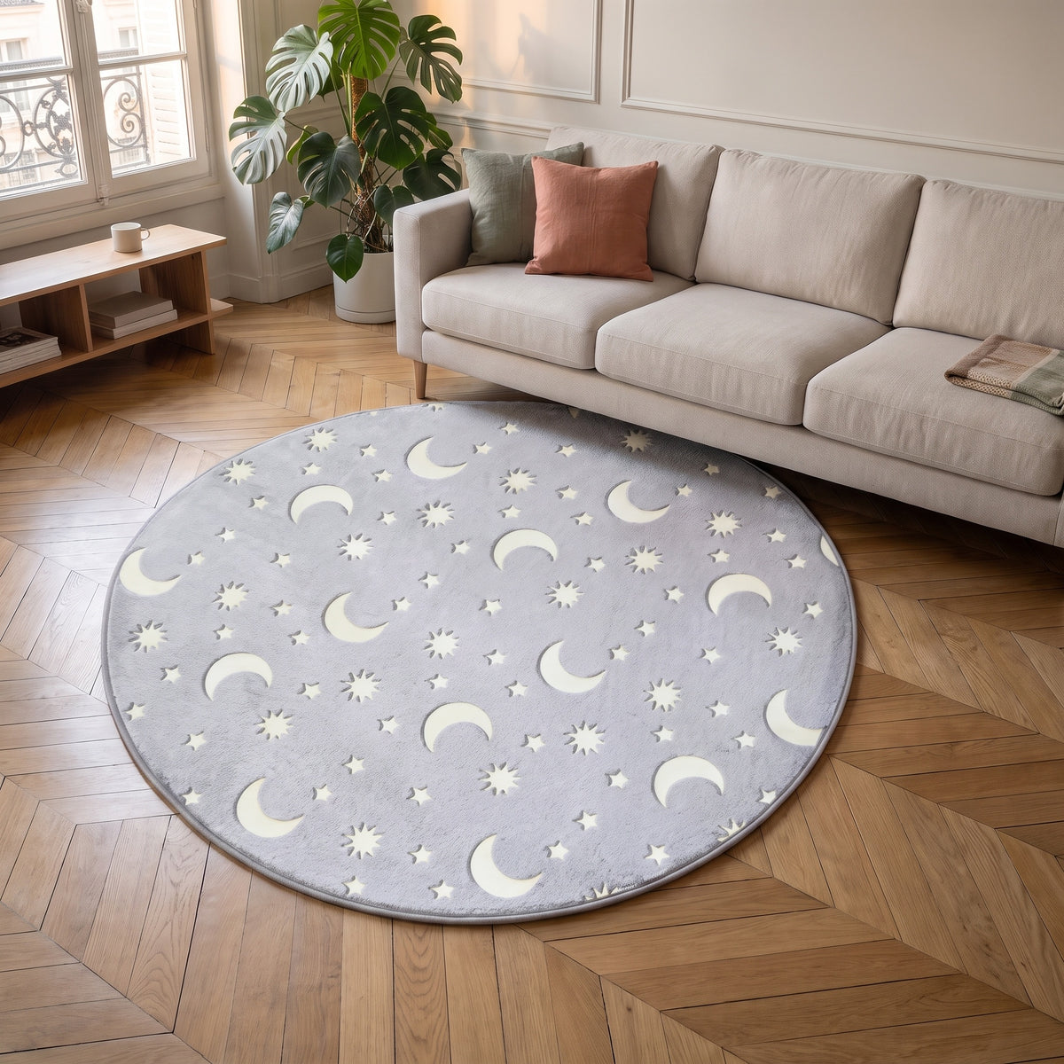 Tapis rond phosphorescent gris à lunes et étoiles devant un canapé