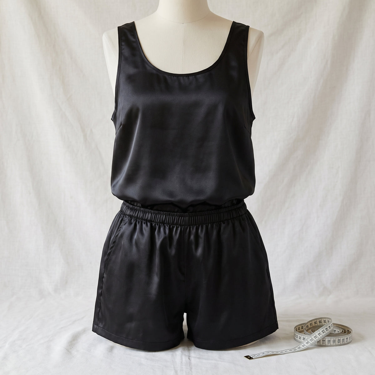 Le débardeur et le short en satin noir sur un buste de couture, un mètre ruban posé à côté Image