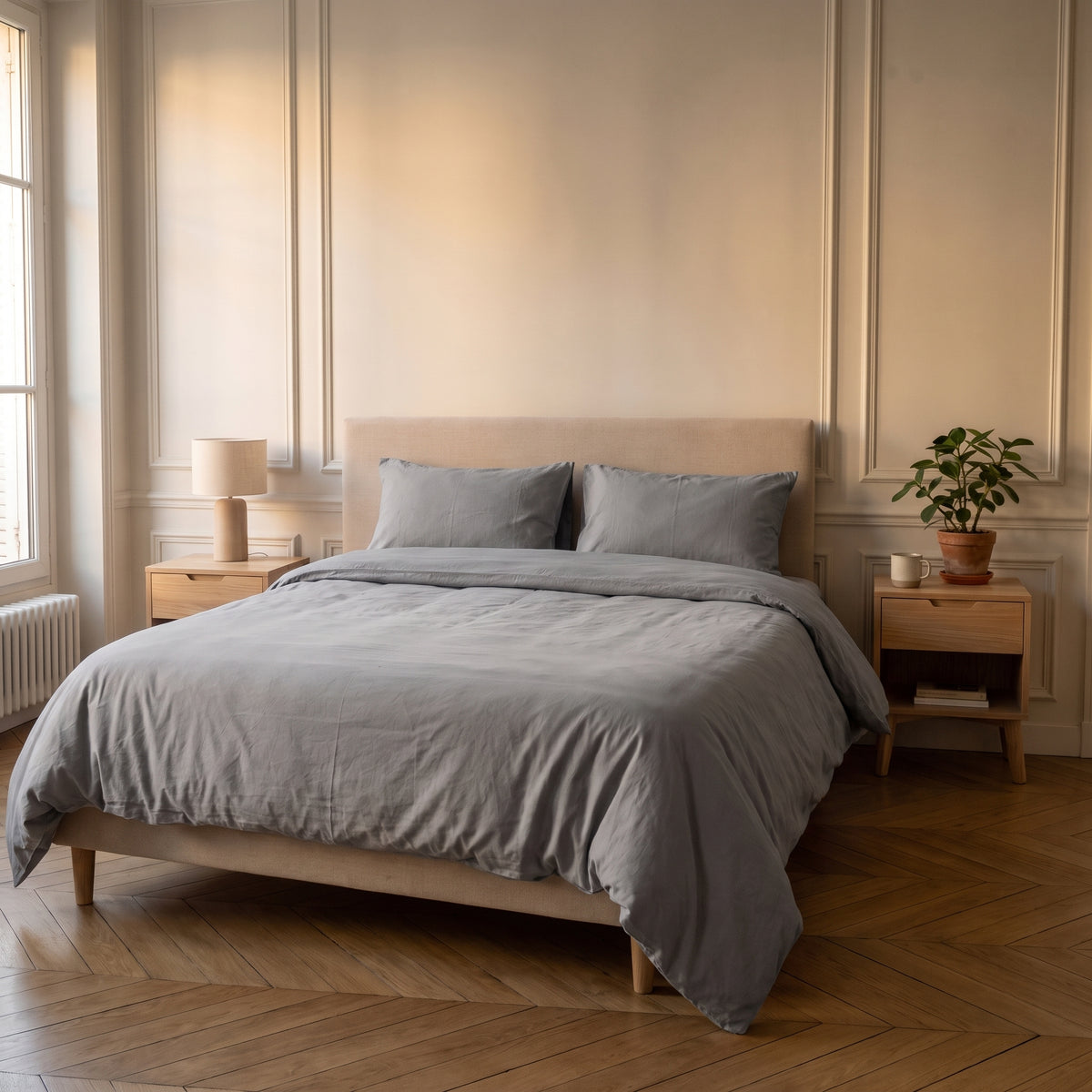 Housse de couette unie gris clair sur un lit dans une chambre lumineuse