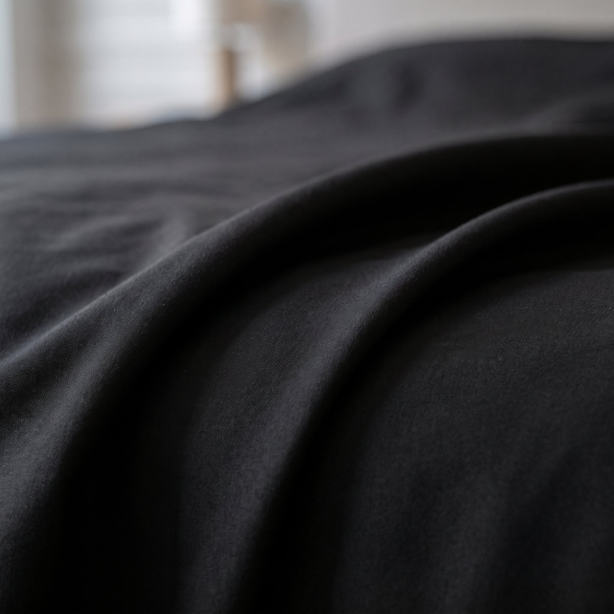 Gros plan sur les plis du linge de lit noir à la surface lisse Image