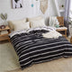Housse de couette rayée noire et blanche sur un lit dans une chambre lumineuse
