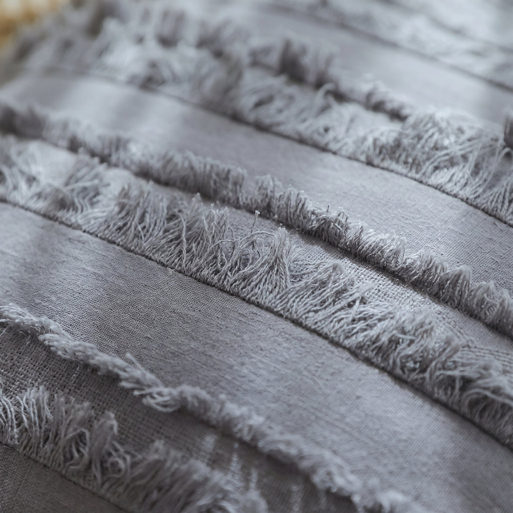 Gros plan sur les franges et le tissage de la housse de coussin bohème grise