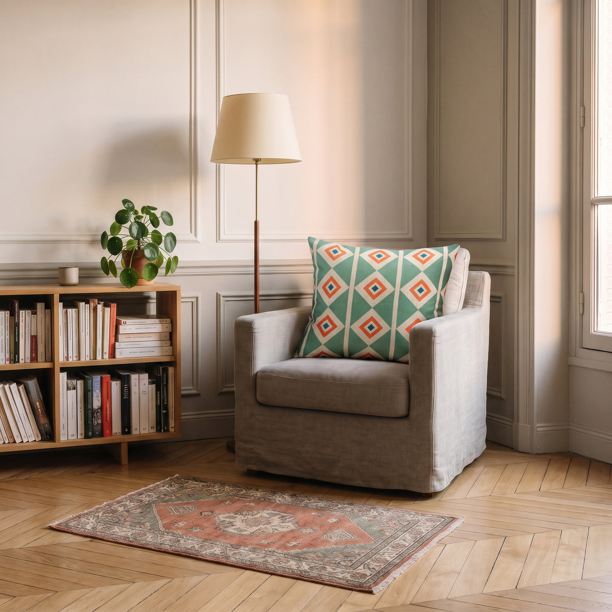Housse de coussin à motif Losanges et rayures vert d'eau, posée dans un fauteuil de coin lecture