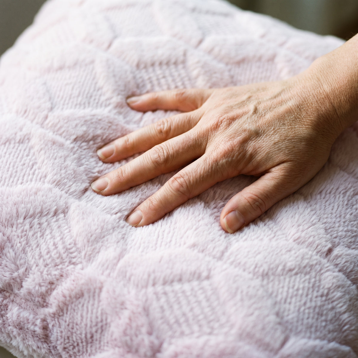 Main posée sur le poil long de la housse de coussin rose clair Image