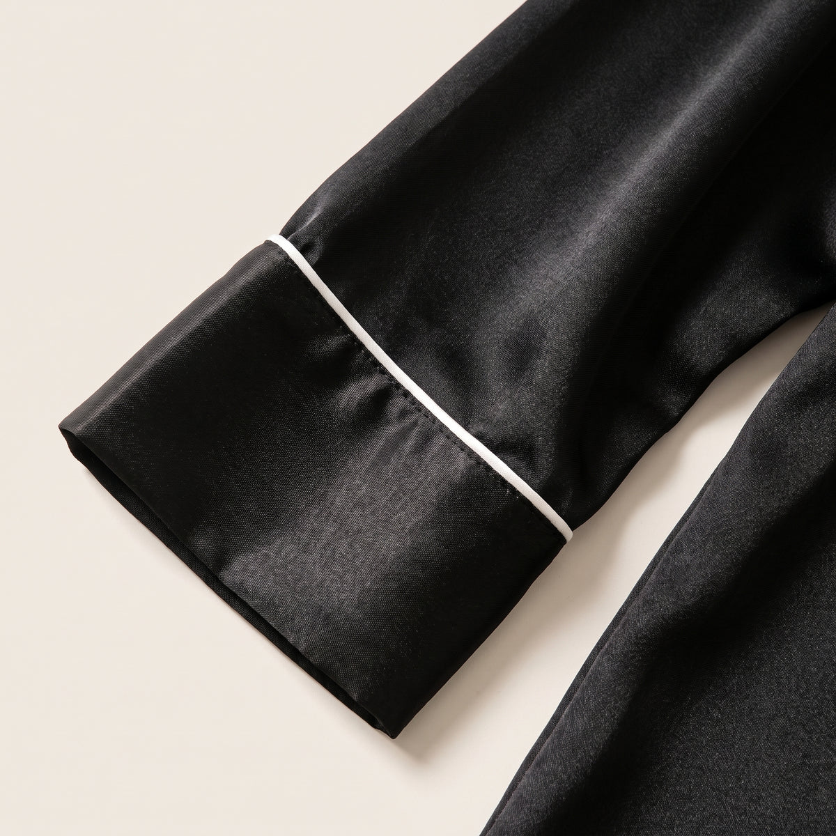 Revers de poignet et liseré blanc au bas d'une manche de pyjama en satin noir Image