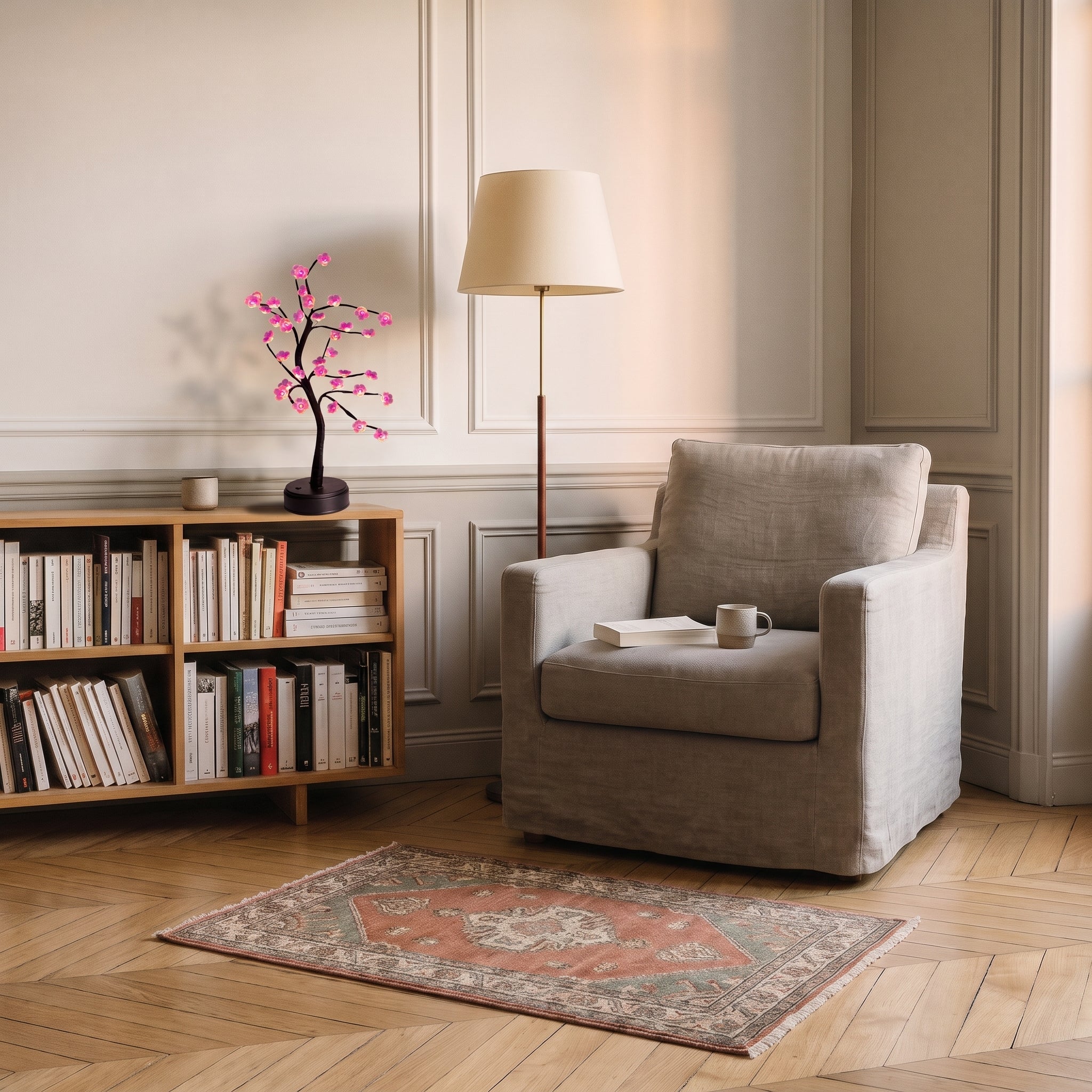 Lampe bonsaï LED à fleurs roses posée sur une table d’appoint près d’un fauteuil de lecture Image