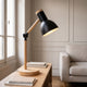 Lampe de bureau pliante noire sur une console près de la fenêtre