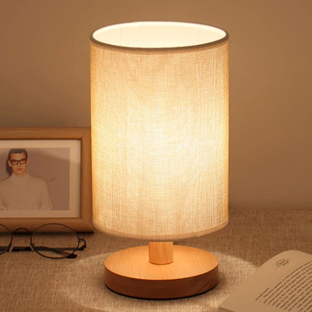 Lampe de chevet en lin uni allumée sur un socle rond en bois
