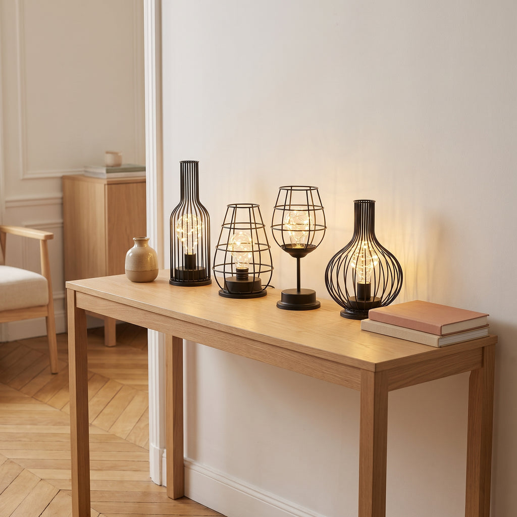 Les quatre lampes de table en fil de fer alignées et allumées sur une console de salon