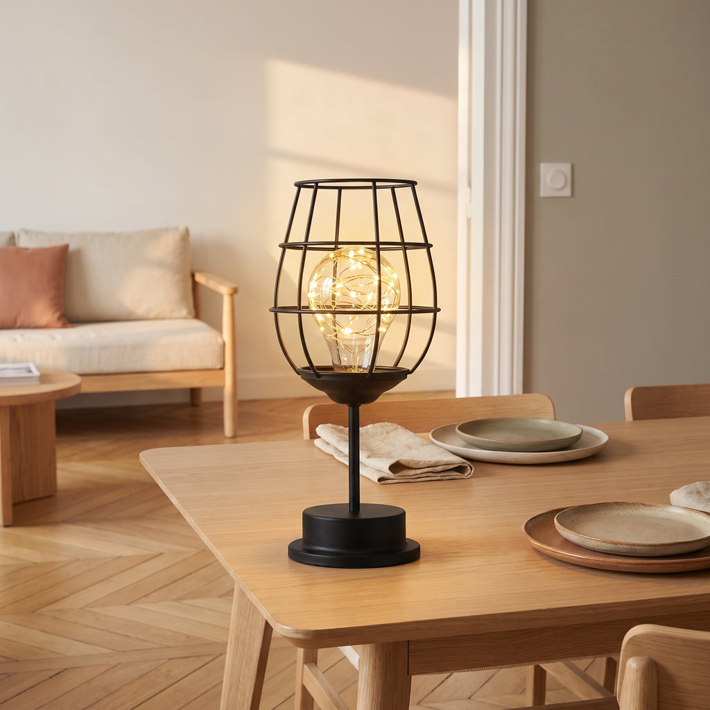 Lampe de table en fil de fer verre à pied allumée sur une table de repas
